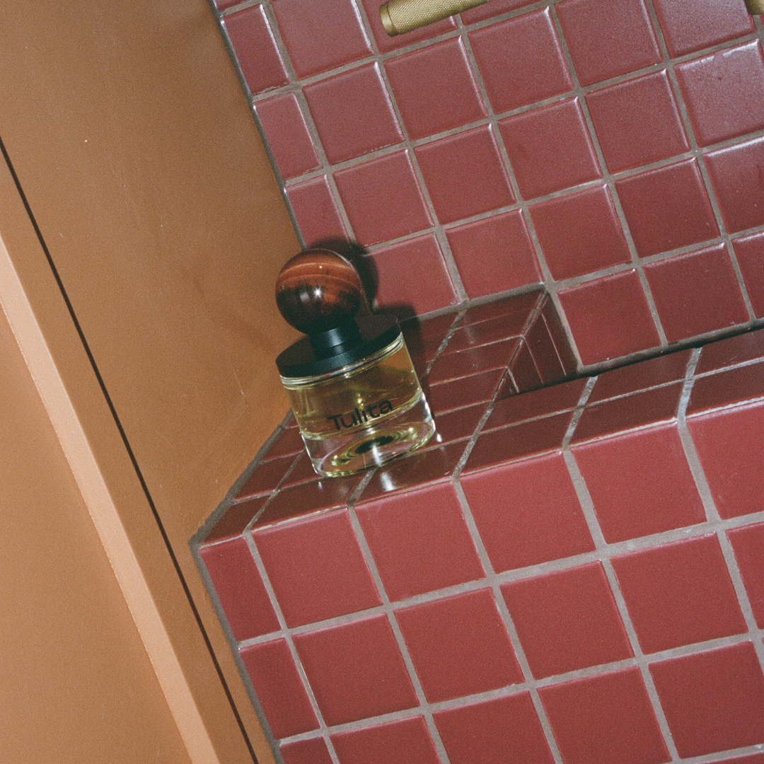Agati bottle sitting on red tile bathroom vanity